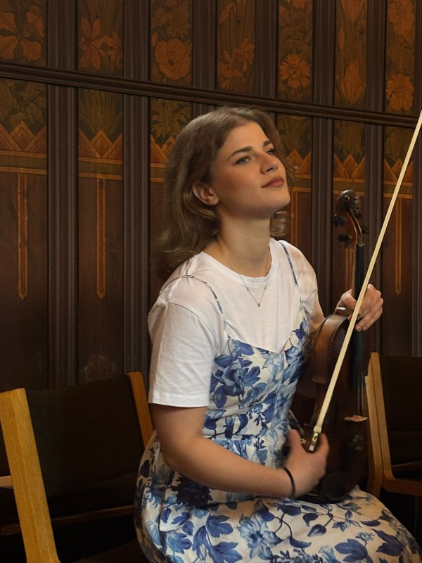Ariadni seated with her violin before a concert