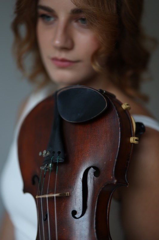 Violin close-up with Ariadni in the background